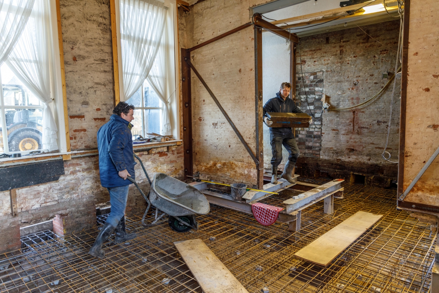 Twee bouwvakkers zijn in een woning bezig fundering te vernieuwen.