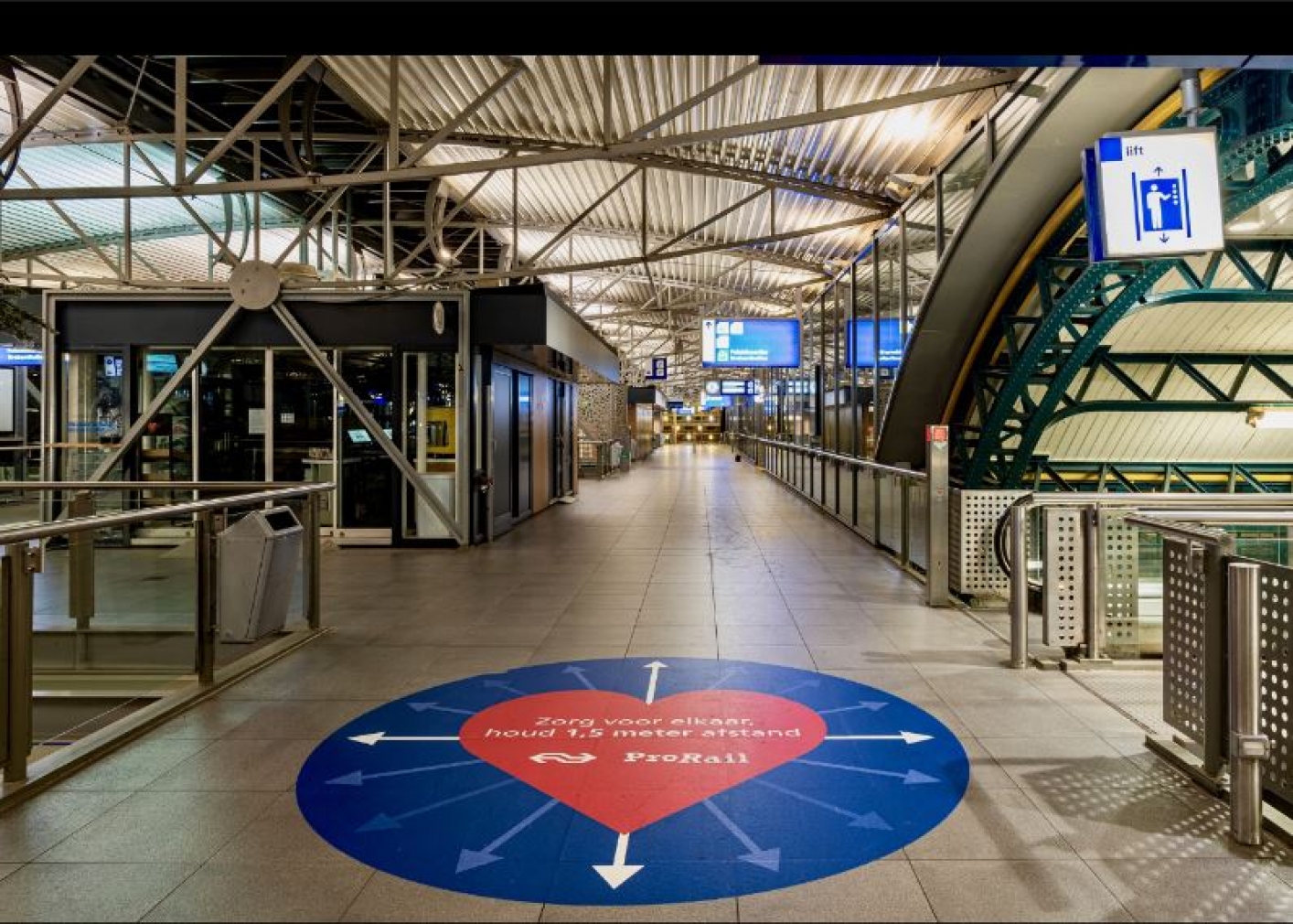 foto van stationstraverse met grote sticker op de grond met tekst 'Zorg voor elkaar, houd 1,5 m afstand'